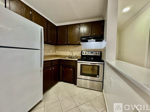 A kitchen with a white refrigerator, stainless steel oven, and brown cabinets.