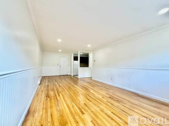 A room with wooden flooring and white walls.