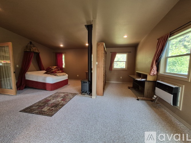 A bedroom with a bed, desk, and window.