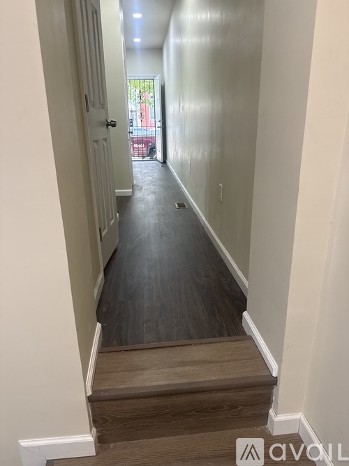 A long hallway with a wooden floor and white walls.