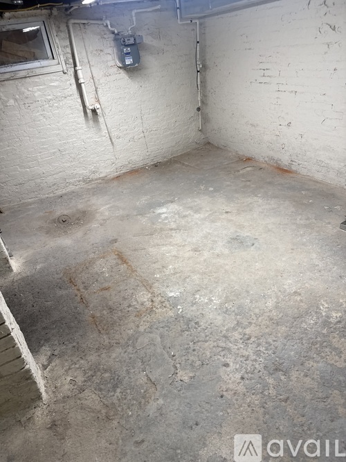 A dirty basement with a white wall and a window.