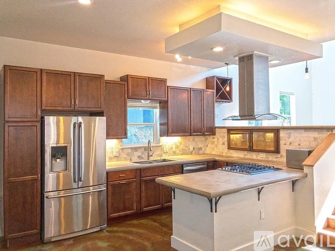 A kitchen with a stainless steel refrigerator and wooden cabinets.