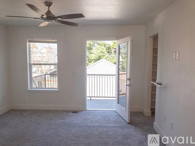 A room with a ceiling fan and a door leading to a balcony.