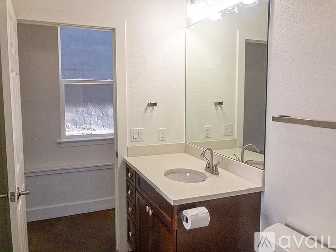 A bathroom with a sink, mirror, and a window.