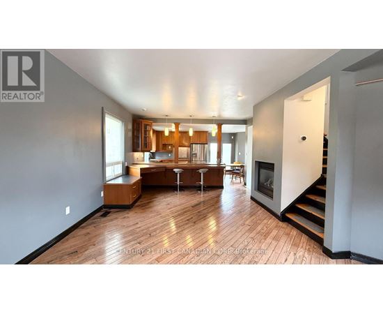 A spacious living room with hardwood floors and a staircase leading to the upper level.