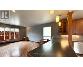 A realtor logo is on a wall in a room with a long table and wooden floors.