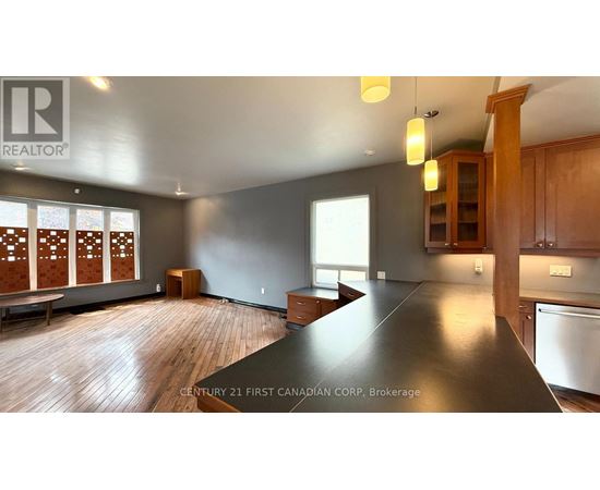A realtor logo is on a wall in a room with a long table and wooden floors.