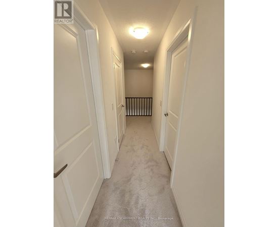 A long hallway with white doors and a carpeted floor.