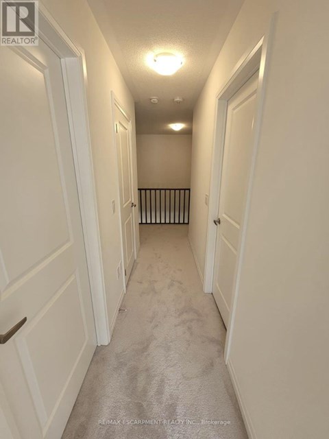 A long hallway with white doors and a carpeted floor.