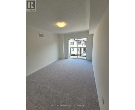 A large, empty room with a carpeted floor and a window with a view of a building outside.