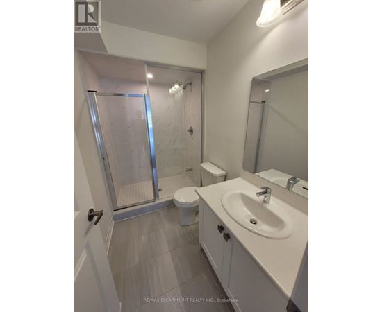 A white bathroom with a toilet, sink, and walk-in shower.