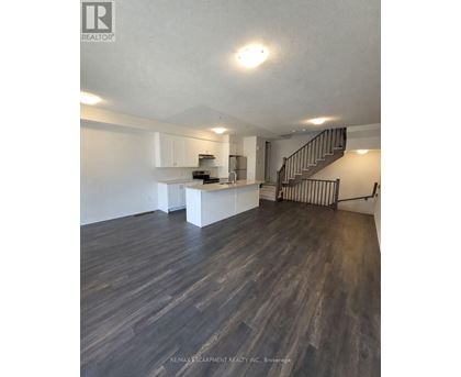 A spacious kitchen and living room with wood flooring and a staircase.