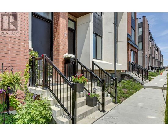 A row of townhouses with a realtor sign on the first one.