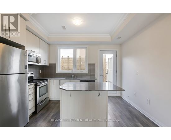 A modern kitchen with a stainless steel refrigerator and microwave.