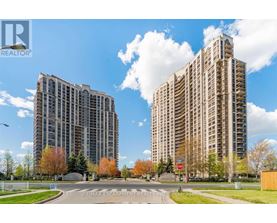 Two tall buildings are situated next to each other with a road in between.