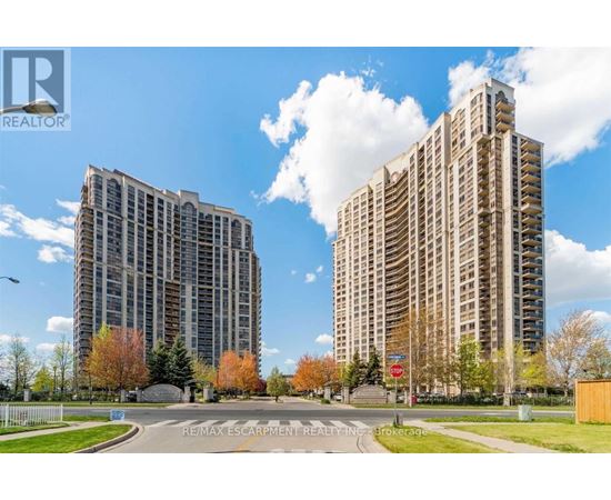 Two tall buildings are situated next to each other with a road in between.