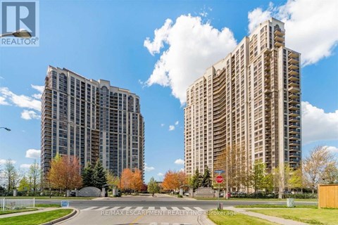Two tall buildings are situated next to each other with a road in between.