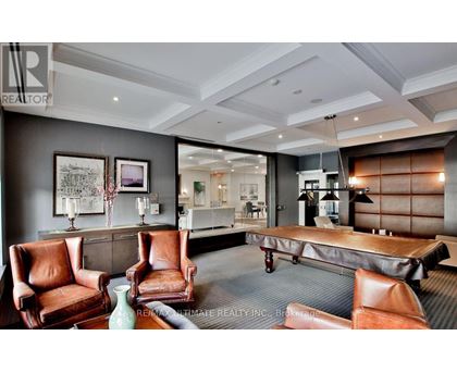 A living room with a grey carpet and brown leather chairs.