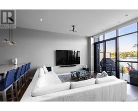 A modern living room with a large white couch and a flat screen TV mounted on the wall.