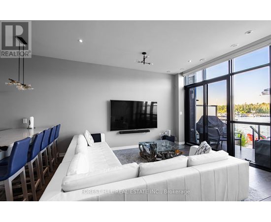 A modern living room with a large white couch and a flat screen TV mounted on the wall.