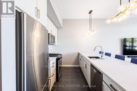 A modern kitchen with a stainless steel refrigerator and a white countertop.