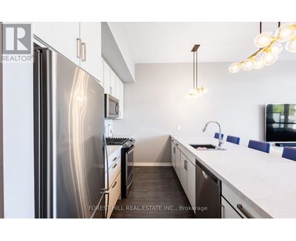 A modern kitchen with a stainless steel refrigerator and a white countertop.