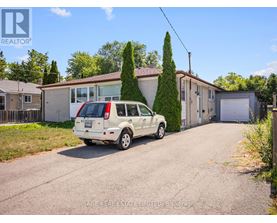 A white car is parked in front of a house with a sign that says REALTOR.