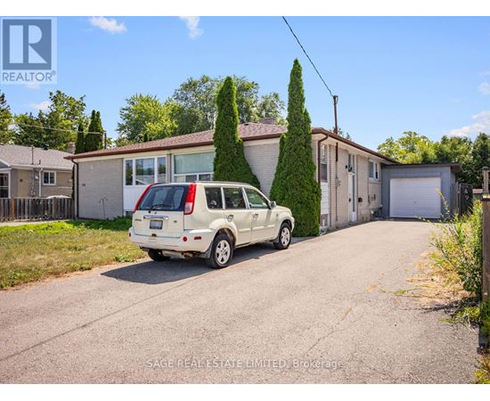A white car is parked in front of a house with a sign that says REALTOR.