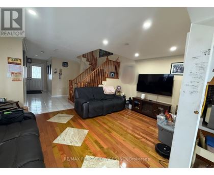 A living room with a black couch and a wooden staircase.