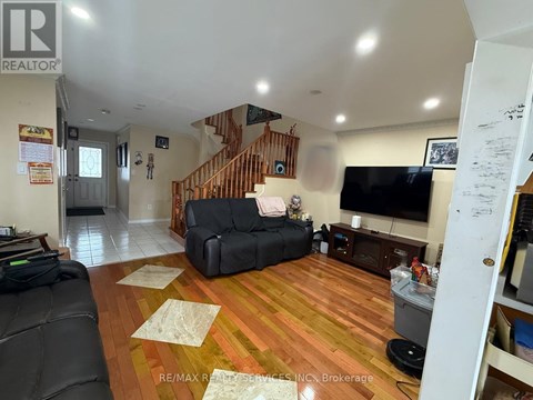 A living room with a black couch and a wooden staircase.