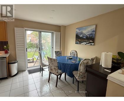 A dining room with a table set for two and a painting of a mountain scene on the wall.