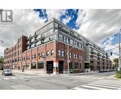 A street view of a multi-story building with a glass facade on the top floor.