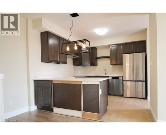 A kitchen with a black and brown island and stainless steel refrigerator.