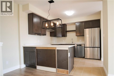 A kitchen with a black and brown island and stainless steel refrigerator.