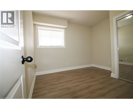 A room with a wooden floor and a window with blinds.
