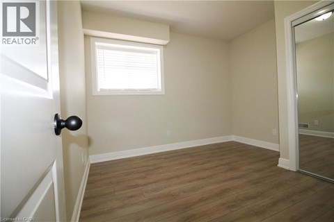 A room with a wooden floor and a window with blinds.