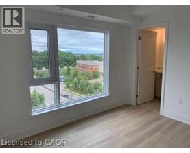 A room with a view of a parking lot and trees through a window.
