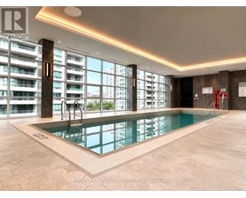 A large indoor swimming pool with a tiled floor and a view of a cityscape through the windows.