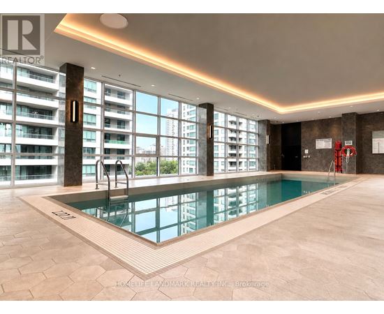 A large indoor swimming pool with a tiled floor and a view of a cityscape through the windows.