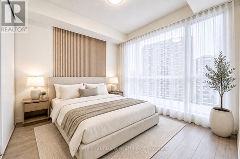 A bedroom with a large bed, a nightstand with a lamp, and a potted plant.