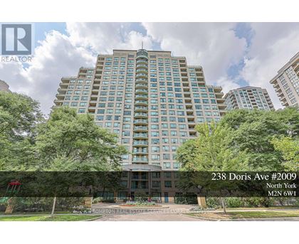 A tall building with many windows is surrounded by trees and has a sign that reads "238 Doris Ave #2009 North York".