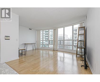 A room with a wooden floor and a ladder leaning against the wall.