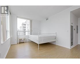 A white bedroom with a bed, nightstand, and window.