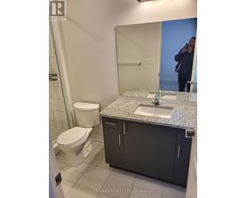A bathroom with a sink, toilet and mirror.