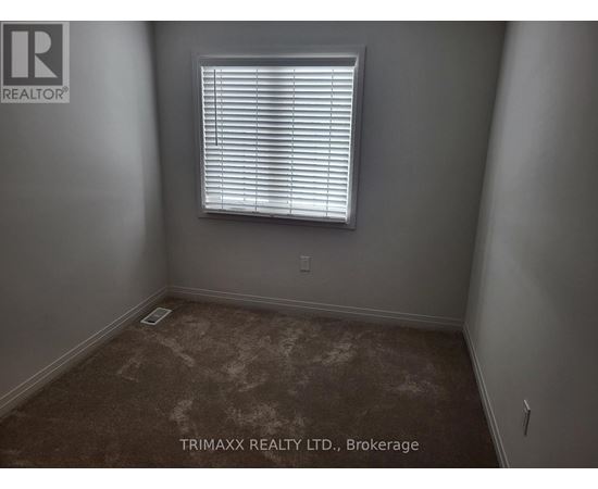 A room with a window and a brown carpet.