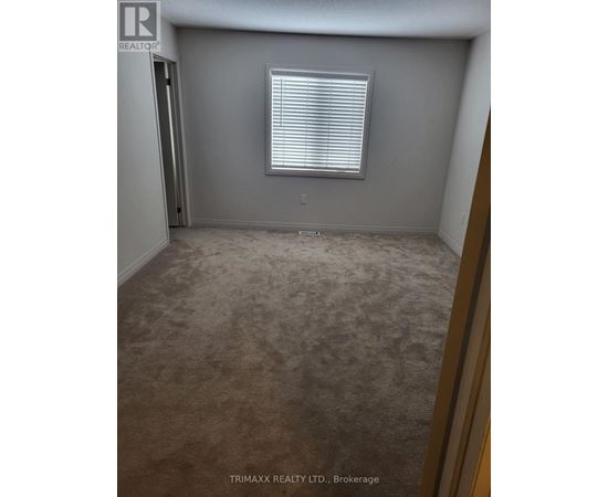 A room with a carpeted floor and a window with blinds.