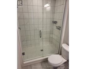 A white toilet sits next to a glass shower stall.