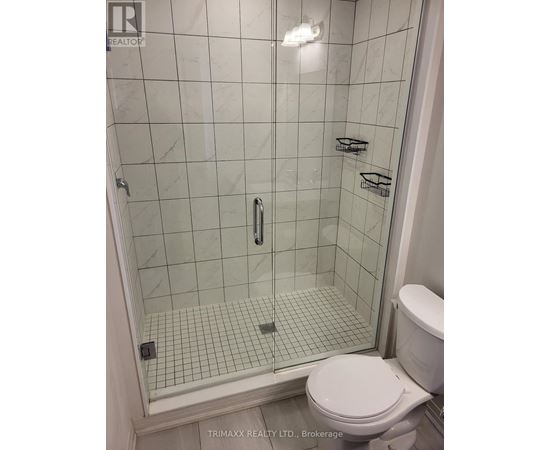 A white toilet sits next to a glass shower stall.