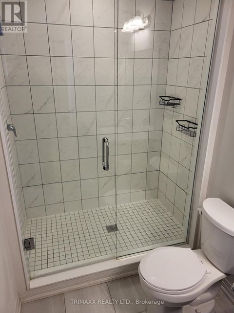 A white toilet sits next to a glass shower stall.