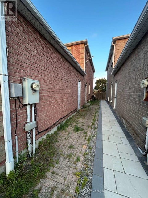 A narrow alley between two brick buildings with a Real Estate sign on the top left.